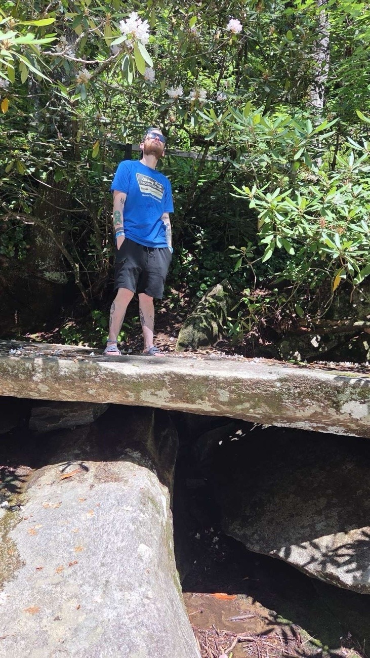 blue shirt, black shorts axton on a rock cave
