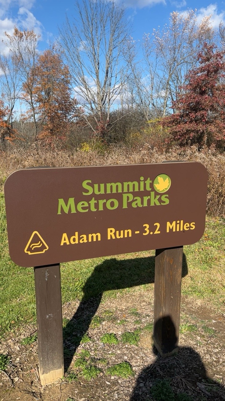 Sign for Adam Run at Metro summit parks brown sign greens & yellow font says trail is 3.2 miles