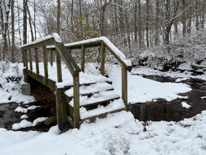 A snow covered bridge crossing a creek 