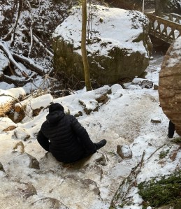 Kelsey in their black coat sliding safely down the stairs