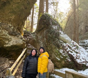 Axton in a yellow jacket and Kelsey in a Black Jacket in front of rocks 